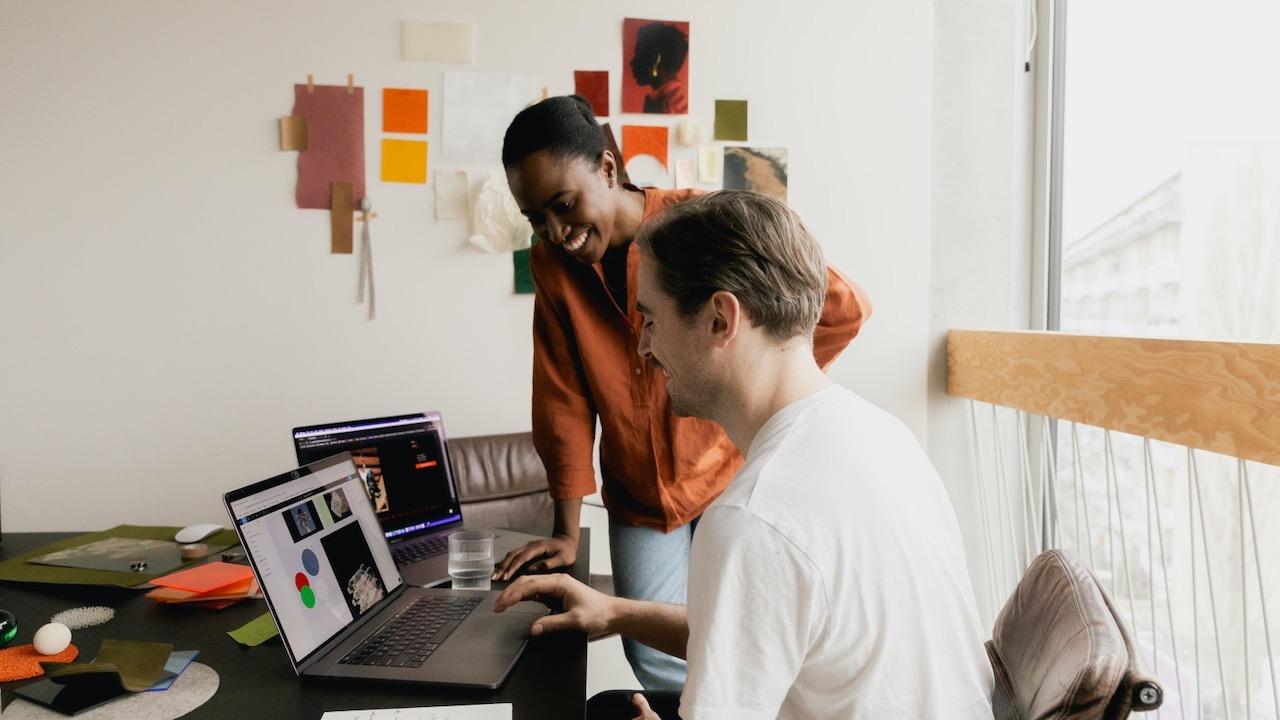 Two people smiling while looking at a laptop screen