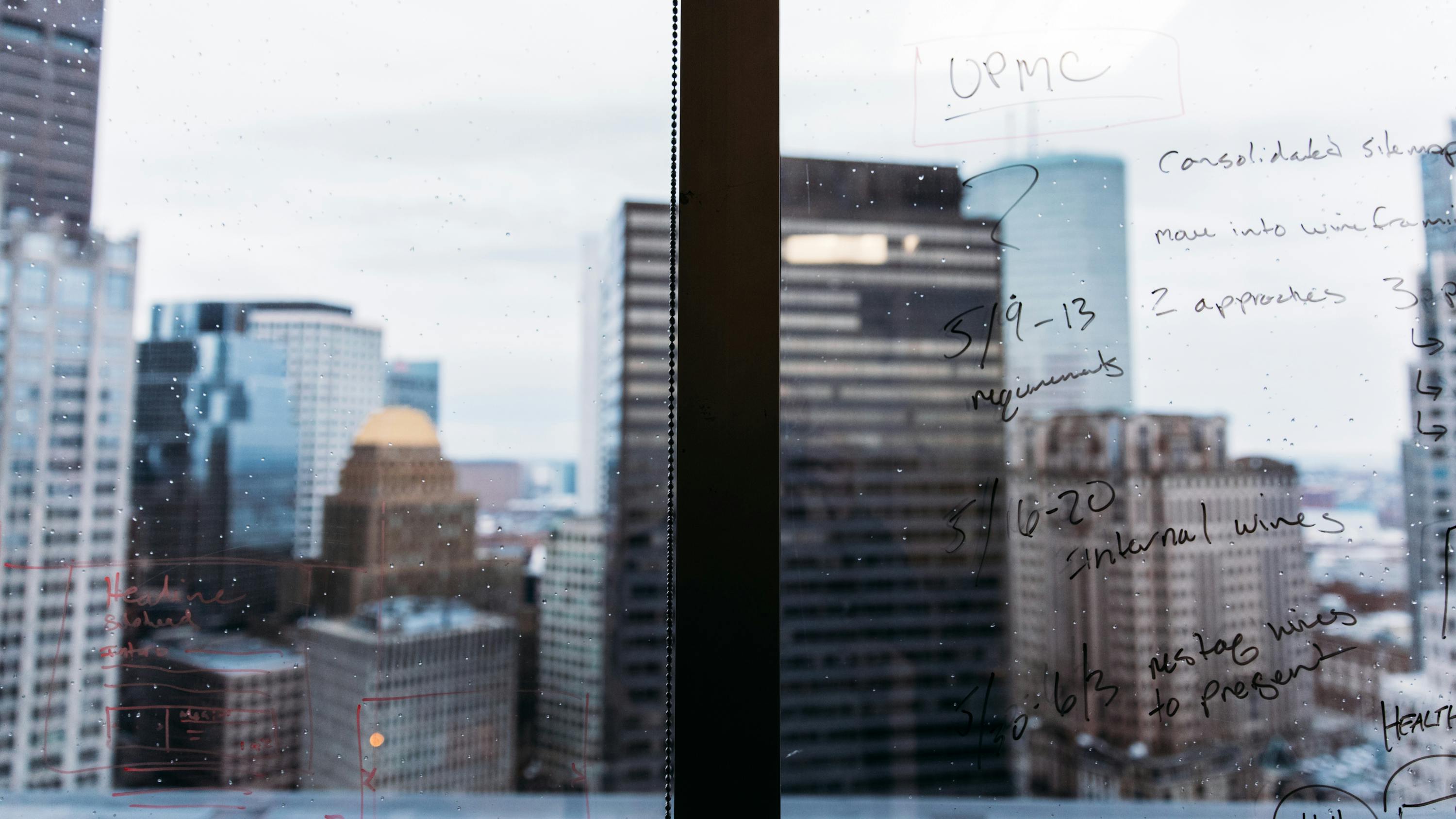 A window with dry erase marker writing on it overlooking a city