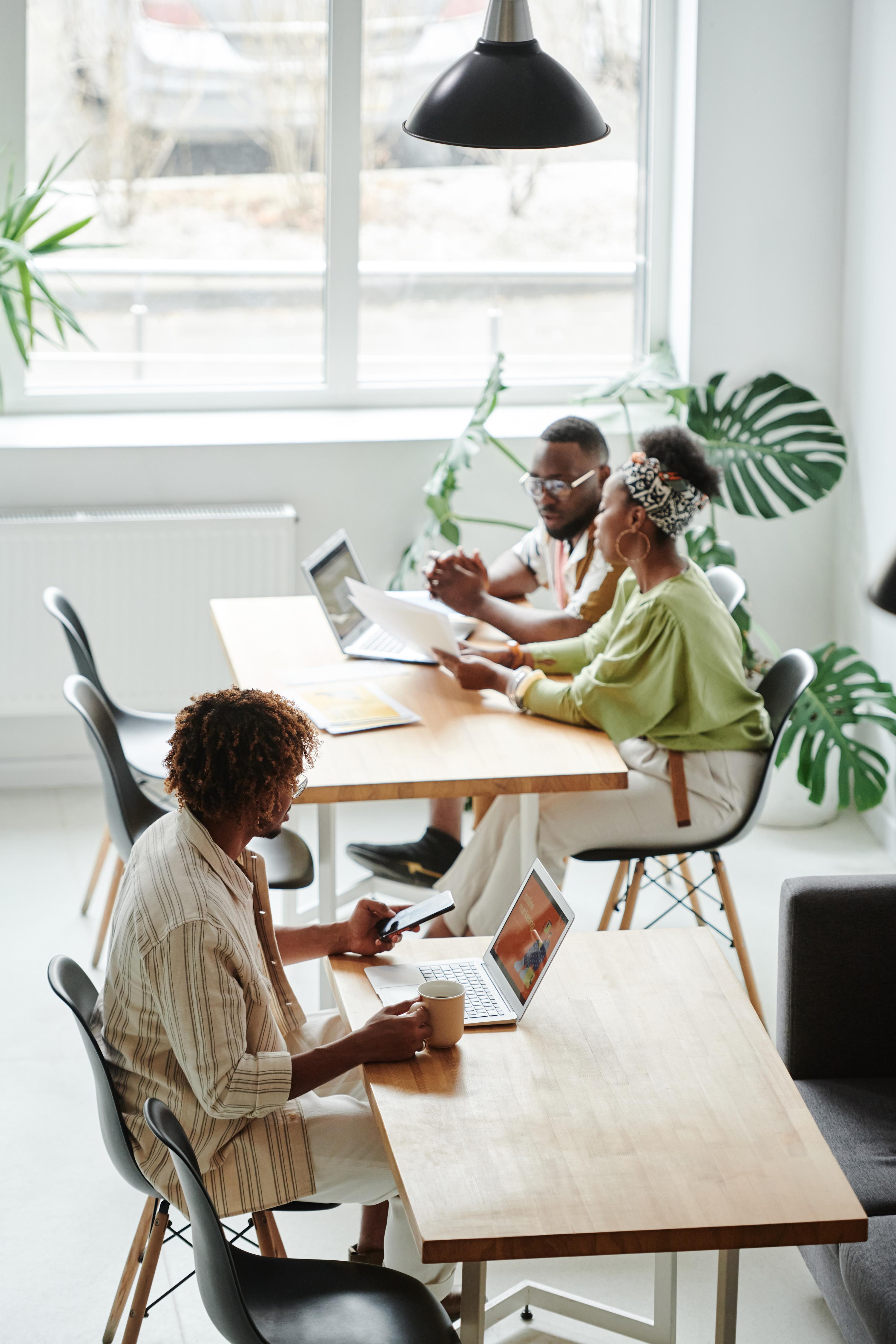 Three people sitting at tables using their laptops