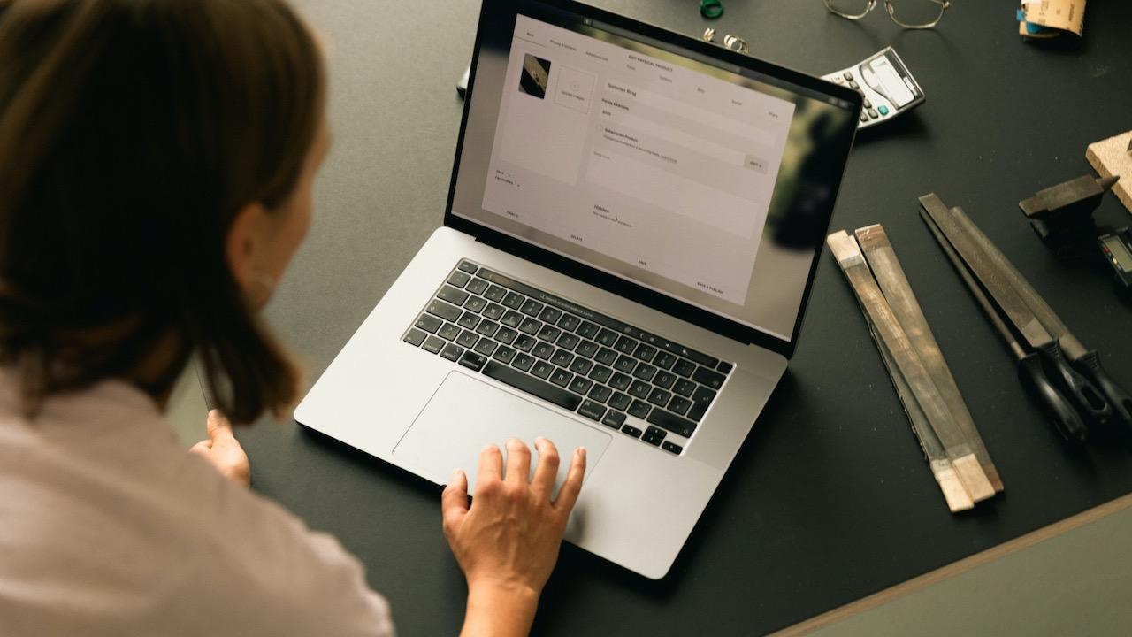 Woman using the trackpad on her laptop sitting at a table