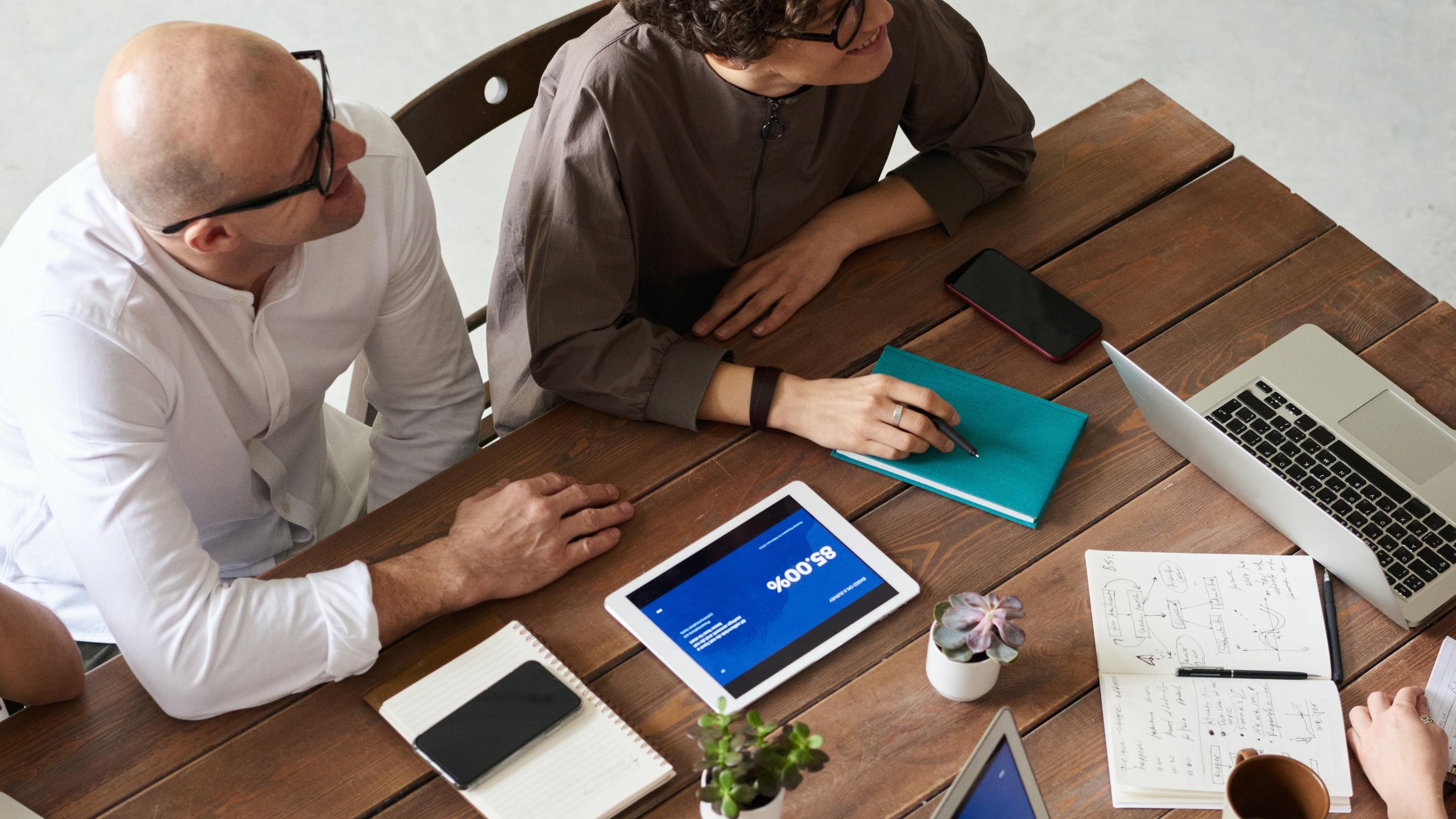 employees meeting at table with laptops