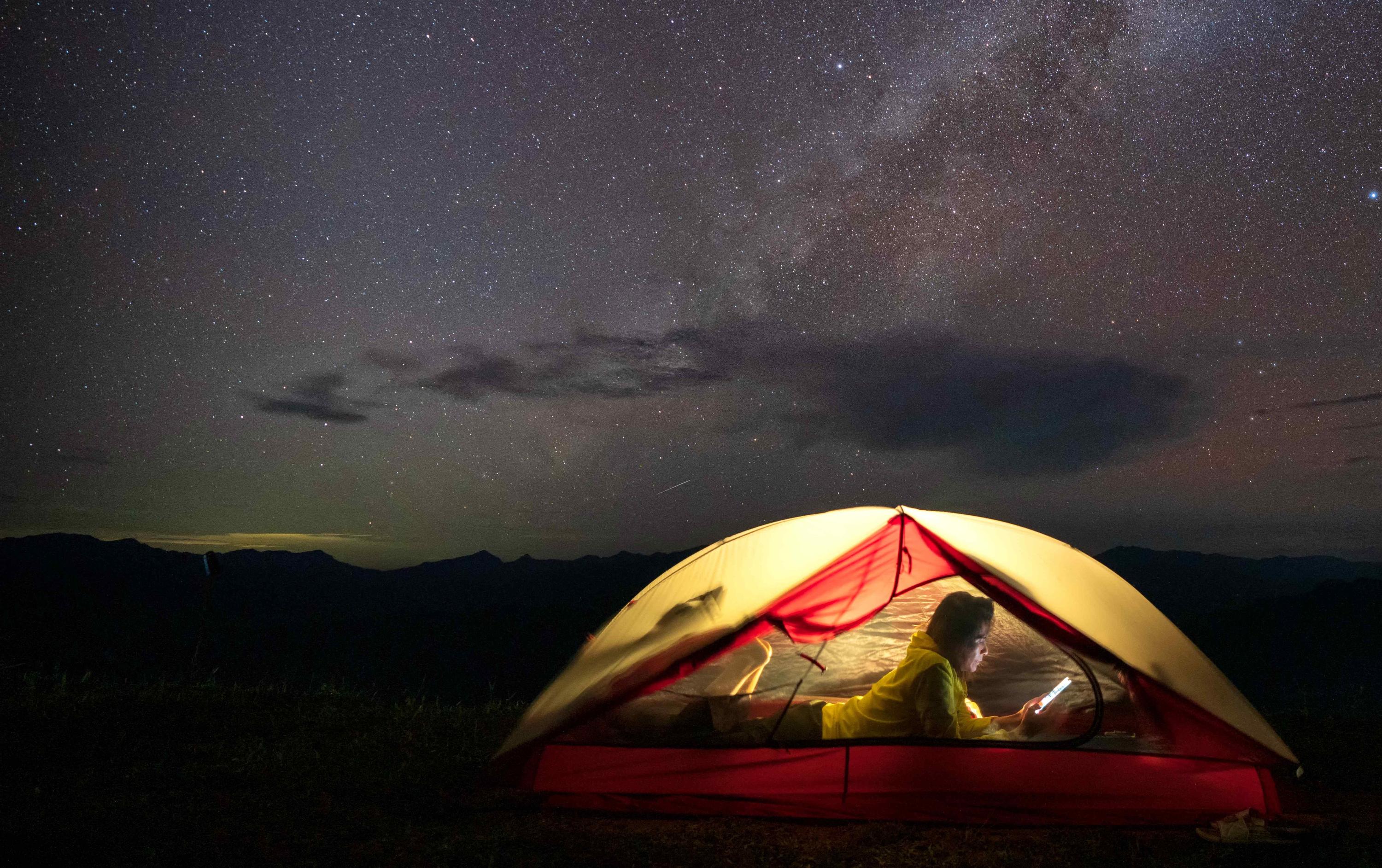 Girl in tent reading IPad under the stars