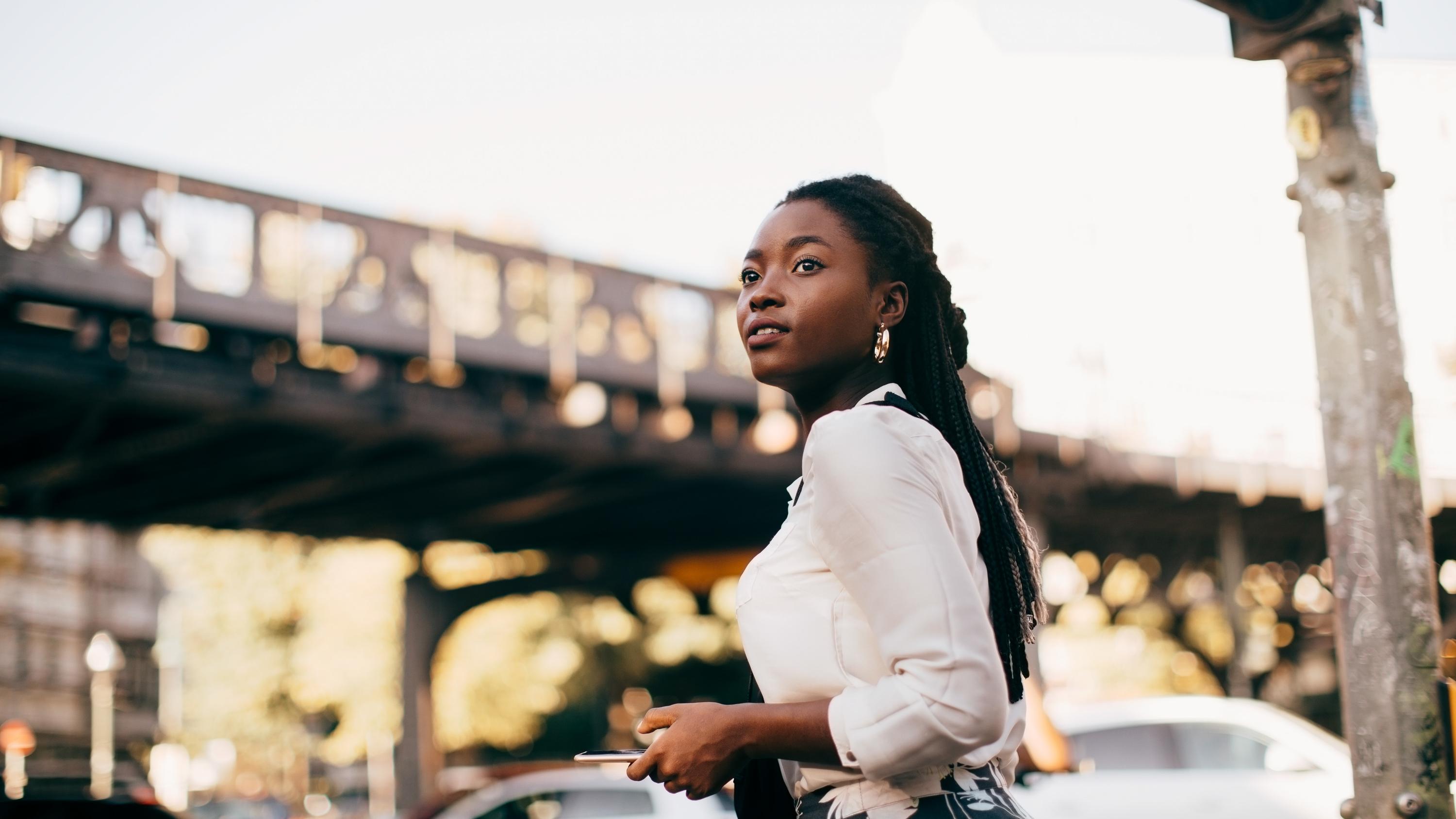 Woman walking through a city holding her smartphone