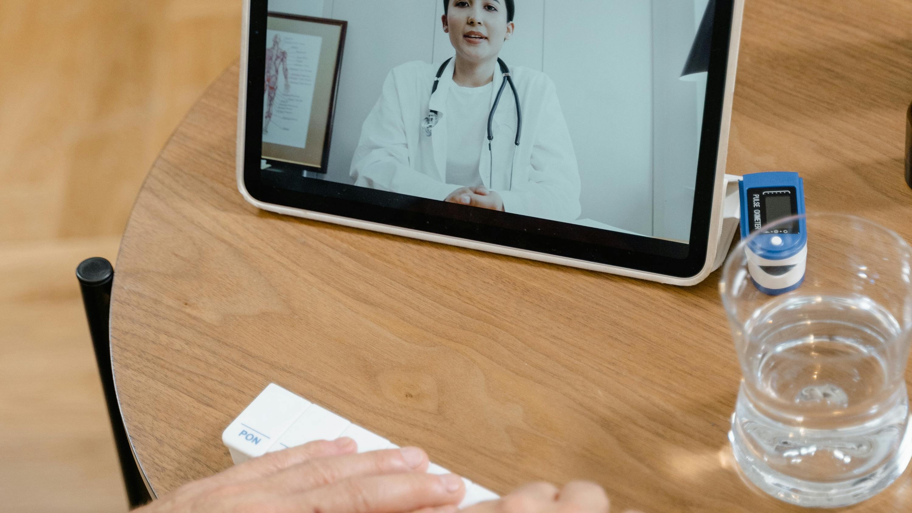Person using their tablet for a telehealth call while holding a pill organizer