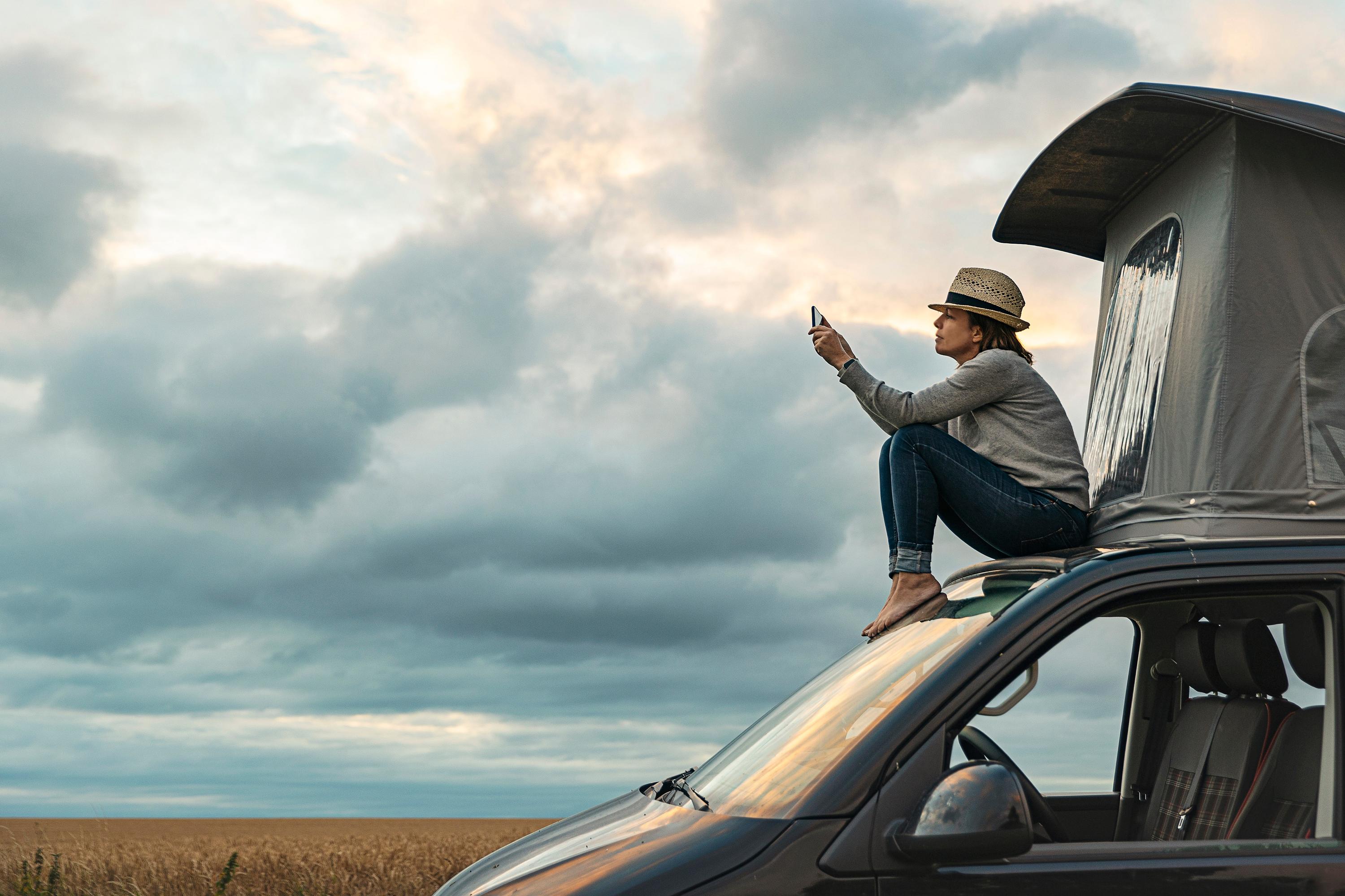 Girl sitting on camper looking at her phone