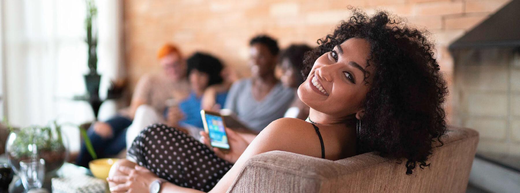 A woman smiling while holding her mobile phone.