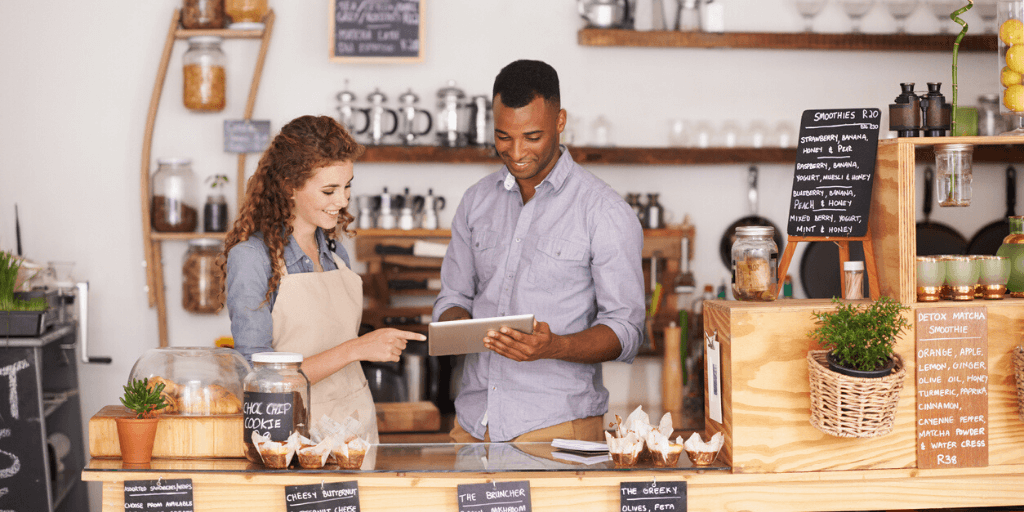 An example of a customer experience and an employee experience. A female employee and a male customer looking at a tablet in a cafe.